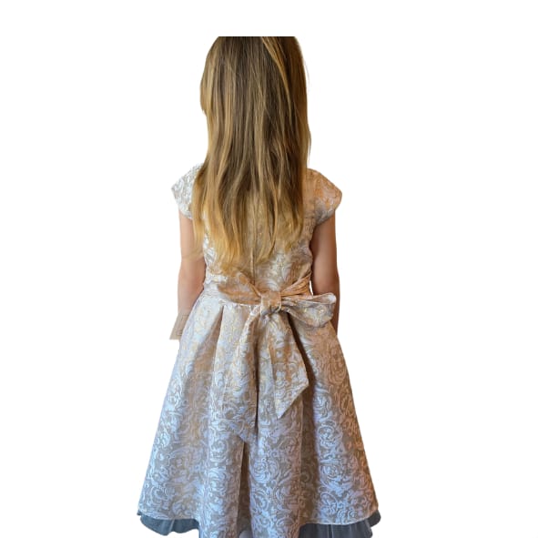 Alt tekst:
Luxe meisjesjurk in champagnekleur met bloemenstructuur en transparante tule zoom uit de Petite Occasion Dresses collectie van Jacobsz Atelier.